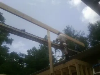Carpenter setting a ridge beam over a new addition frame — Ice Dam Removal by Roofing Brothers in Cambria Heights