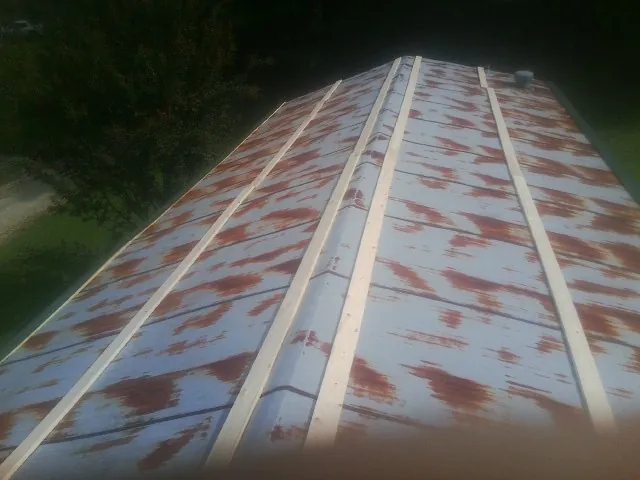 Rusted metal roof panels with new wood purlins before replacement — Storm Damage Roof Repair in Cambria Heights by Roofing Brothers