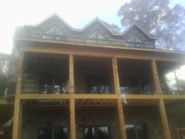 Dormers and porch framing on a large log home under construction — Roof Coating work by our crew in Cambria Heights
