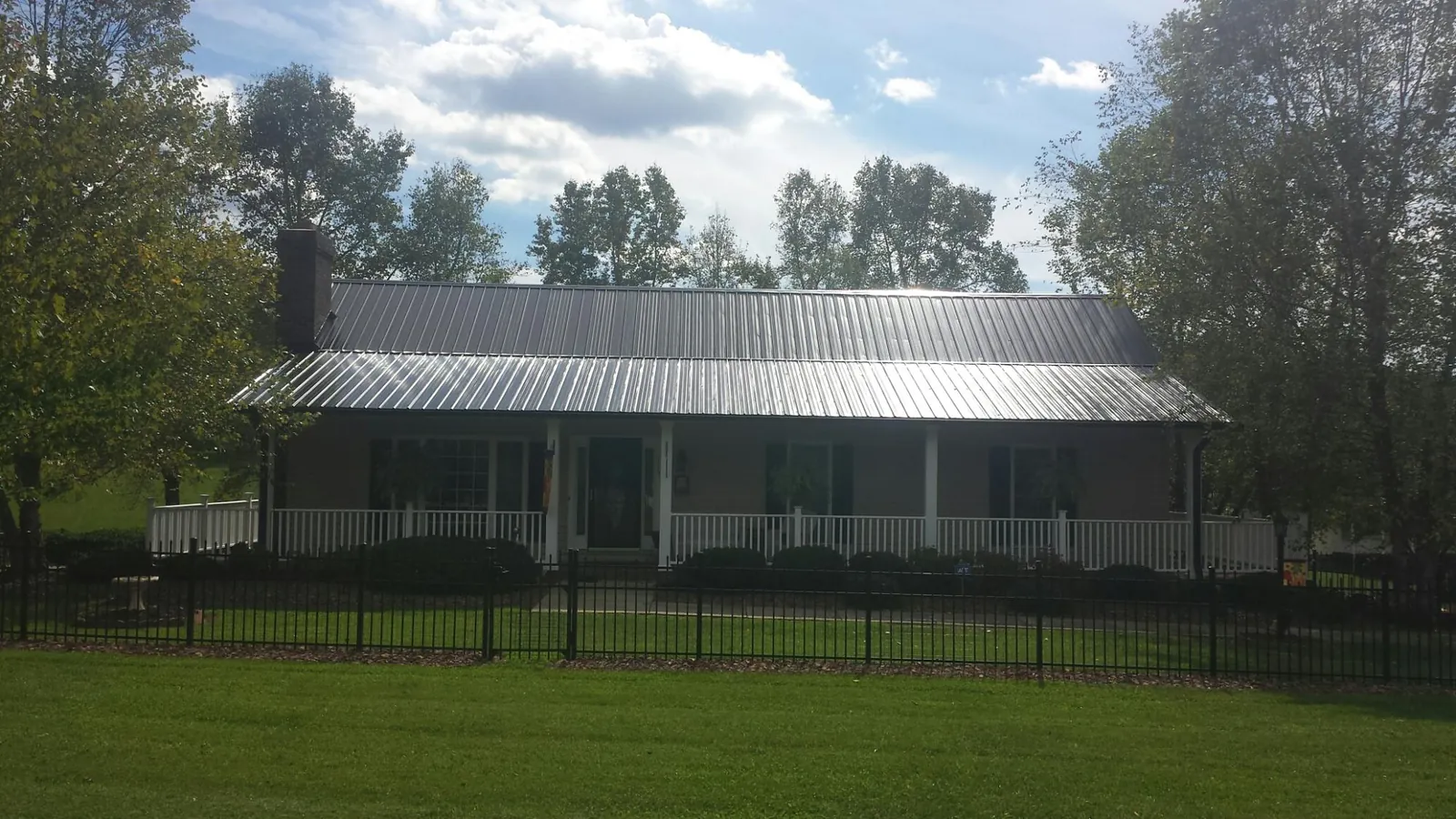 Gray metal roof on a brick ranch with a full width front porch — Gutter Guard Installation work by our crew in Cambria Heights